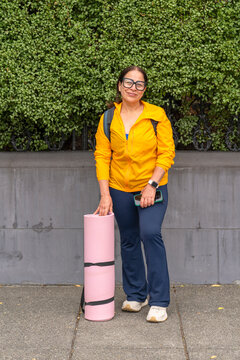 portrait of mature woman in activewear with yoga mat