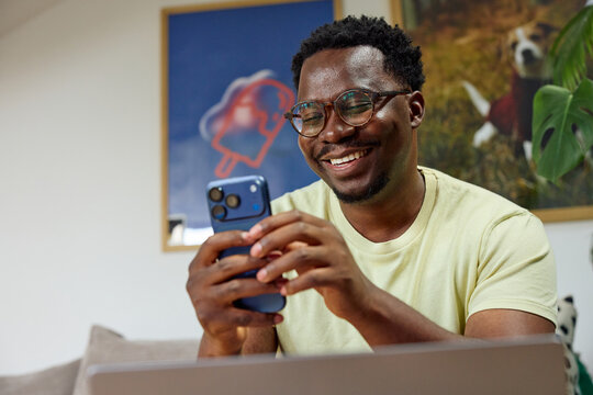 Happy man sits at home, checking his phone