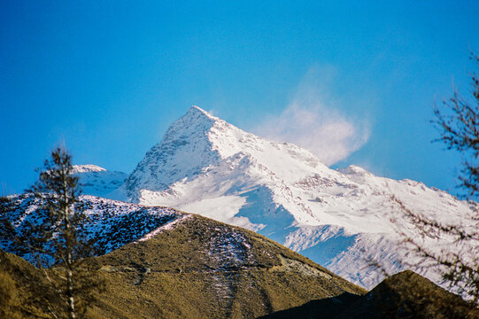 Prominent Snowy Summit with Windswept Clouds