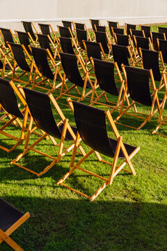 Rows of Empty Black Deck Chairs on a Green Lawn