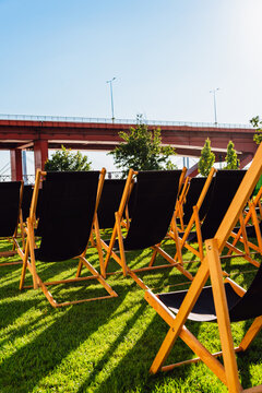 Empty Black Deck Chairs Beneath a Red Bridge