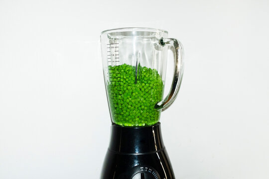 Modern kitchen tool blender full of bright green healthy fresh peas