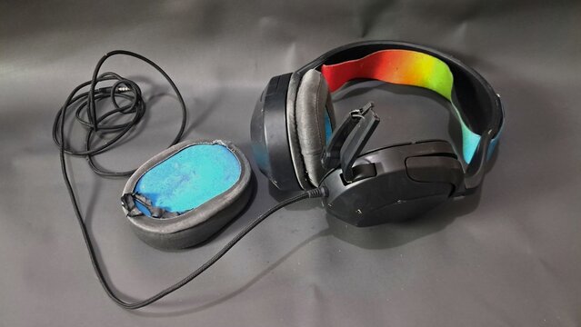 Damaged headset with a broken microphone, showing worn and defective audio equipment isolated in a simple setting. The image represents technology failure, electronic device damage