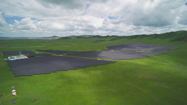 High-Angle Aerial View of Solar PV Panel Array on Zoige Grassland Mountains, Aba, Sichuan: Renewable Clean Energy, Agrivoltaics, Green Hills, Blue Sky and Cloud Background