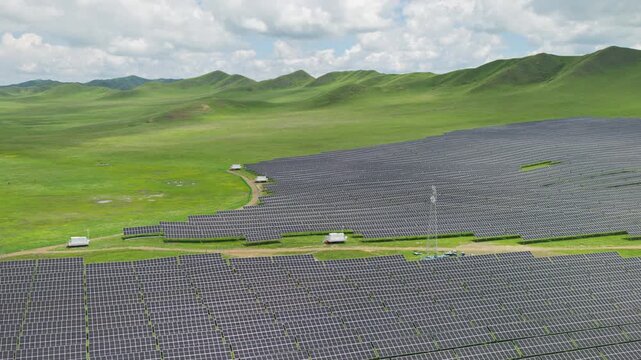 High-Angle Aerial View of Solar PV Panel Array on Zoige Grassland Mountains, Aba, Sichuan: Renewable Clean Energy, Agrivoltaics, Green Hills, Blue Sky and Cloud Background