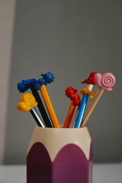 Vertical shot of colorful wooden pencils with animal figure toppers standing in holder cup. Ideal for pediatric clinic, early childhood education and medical care promotion