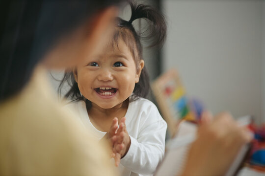 Happy Asian toddler girl clapping hands during medical checkup with pediatrician. Image suitable for pediatric healthcare, child wellness, and early childhood development campaigns