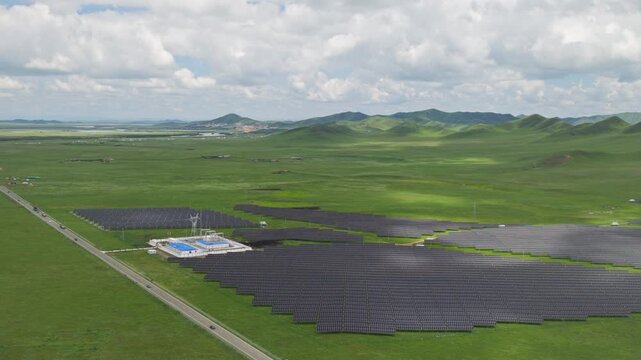 High-Angle Aerial View of Solar PV Panel Array on Zoige Grassland Mountains, Aba, Sichuan: Renewable Clean Energy, Agrivoltaics, Green Hills, Blue Sky and Cloud Background