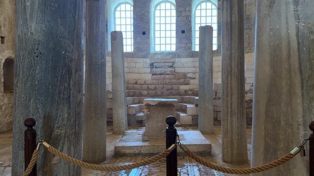 Interior view of the Church of Saint Nicholas in Turkey, showcasing ancient stone columns, a central altar, and large windows illuminating the historic architecture