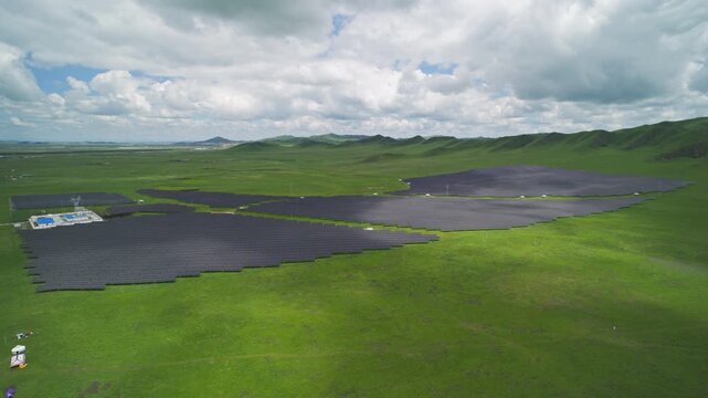 High-Angle Aerial View of Solar PV Panel Array on Zoige Grassland Mountains, Aba, Sichuan: Renewable Clean Energy, Agrivoltaics, Green Hills, Blue Sky and Cloud Background