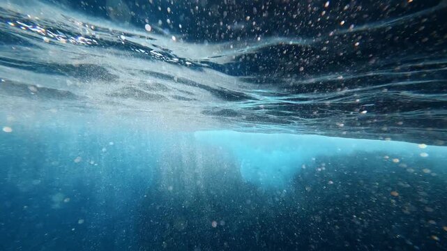 Underwater view of rippling surface and and bubbles in blue water