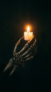 Close view of a burning candle held by a skeletal hand, creating a dark supernatural Halloween 2026 ritual scene with flickering firelight