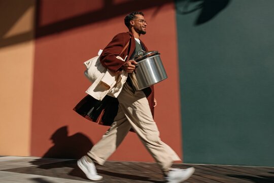 Southeast Asian man carrying a steel slow cooker for thanksgiving dinner, cheerful and hurried with motion blur and copy space