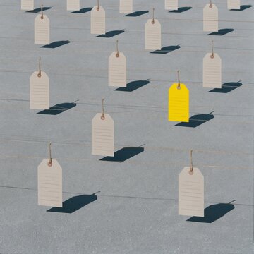 Import tariffs represented by khaki kraft price tags on a grey concrete surface, featuring one yellow accent tag for business concepts