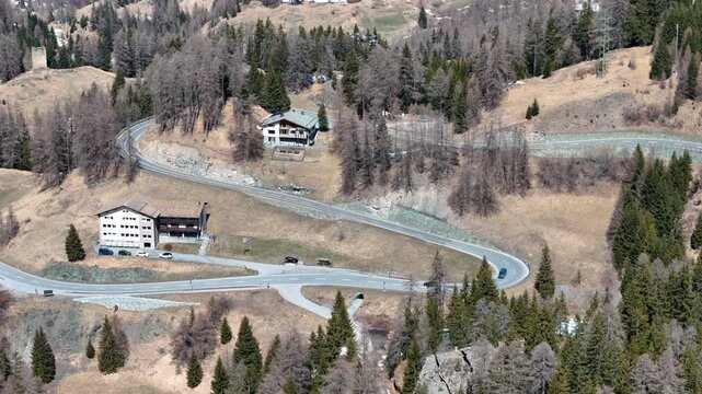 ruined stone tower stands above marmorera resettled village hairpin road switchbacks chalet rooftops parked cars sparse larch trees frame valley floor julier pass drone footage graubunden switzerland