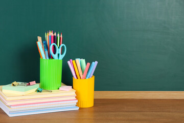 Books, notebooks and stationery on wooden table against chalkboard. Space for text © New Africa