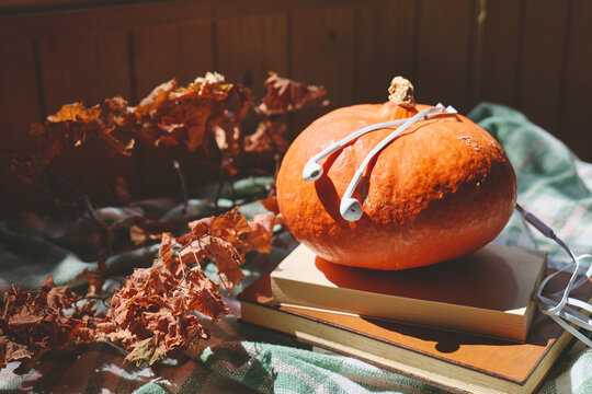 Autumn Audiobook Listening Concept with Books, Pumpkin and Earphones