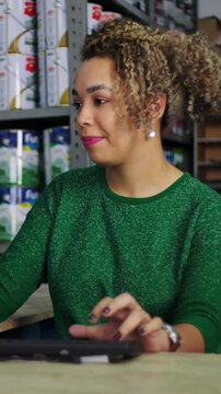 Hispanic woman operating computer at hardware store desk with focused smile representing retail productivity