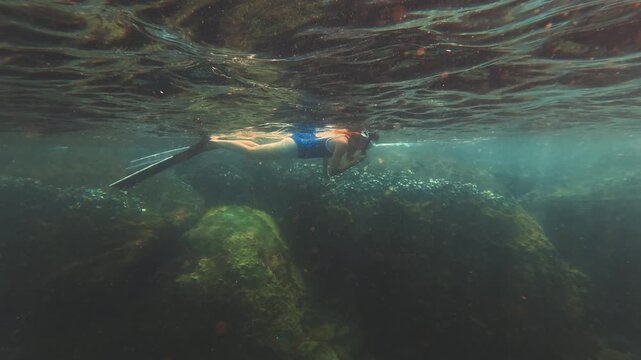 Young slim woman swims underwater, freediving and snorkeling in the sea near the coral reef near the island of Ilha Grande in Brazil