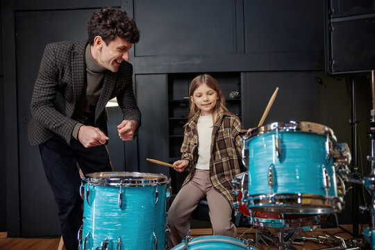 Mentor guides young girl through her drumming lesson in inviting studio setting