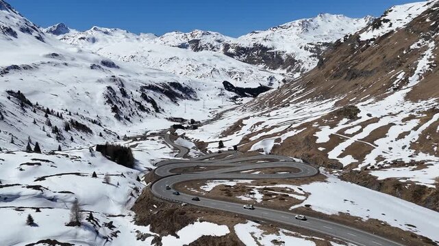 switchback road loops through snowbound valley cars climb hairpin bends toward tunnel portal julier pass mountain crossing graubunden switzerland connects chur engadin valley st moritz alpine route