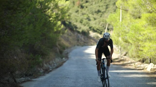 Cyclist Riding Road Bicycle Uphill On Forest Asphalt Road. Endurance Athlete Workout 