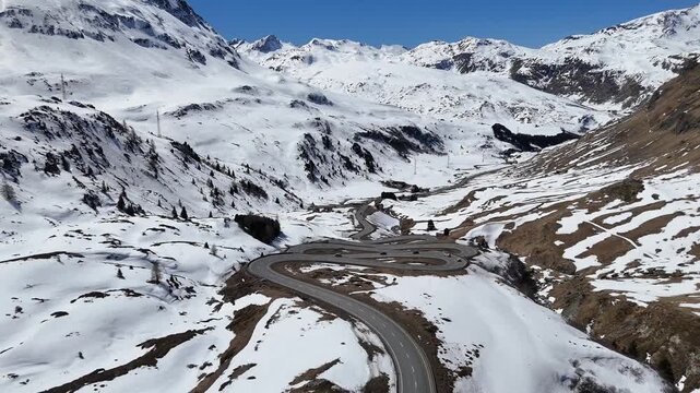 serpentine mountain road curls beneath snowcapped ridgeline wide alpine valley opens toward distant peaks julier pass switchback crossing graubunden switzerland linking engadin valley st moritz chur