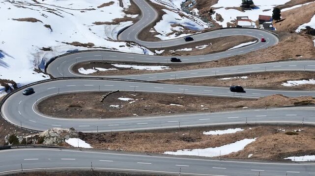 hairpin bends trace tight loops down snowbound slope guardrail asphalt cars descend julier pass mountain crossing graubunden switzerland high altitude route linking engadin chur