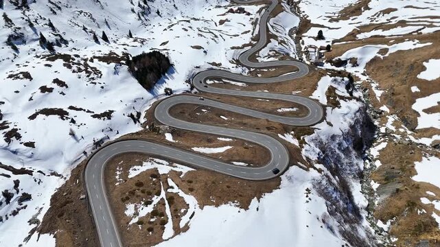 snowbound hairpin bends wind past dark rocky outcrop sparse cars descend julier pass mountain crossing graubunden switzerland high altitude alpine route