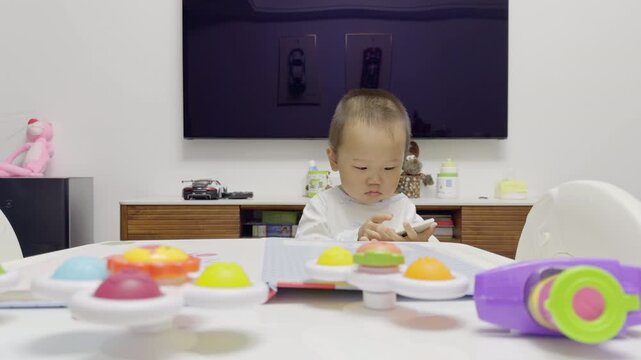 Half-length view of two-year-old toddler playing with colorful tabletop toy