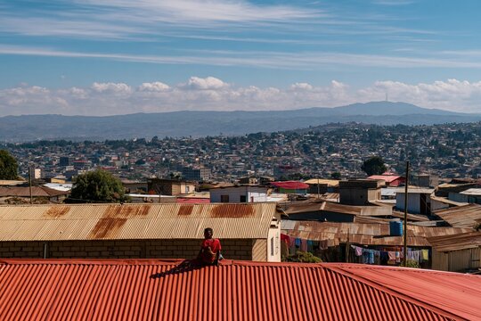 Addis ababa cityscape with weathered corrugated rooftops and a person sitting under a bright midday sky, for urban development and city planning