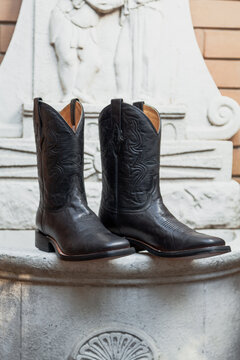 Embossed black leather boots against a white wall