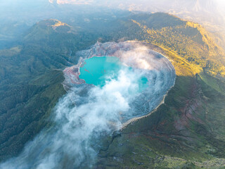 Turquoise lake nestled within a volcanic crater. Mist curls from the crater edge at Mount Ijen © Cloudyew