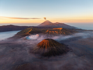 Majestic volcanoes rise above misty valleys at dawn. Soft light bathes rugged peaks in golden hues at Bromo © Cloudyew