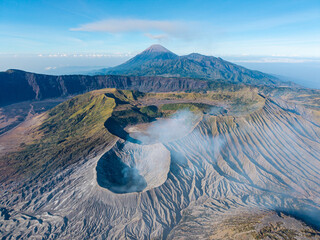 Aerial panorama of Mount Bromo rugged caldera, volcanic slopes, and Mount Semeru rising above clouds in Java, Indonesia. © Cloudyew