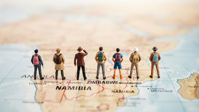 Group of diverse travelers standing on a map in Namibia with backpacks and casual clothing