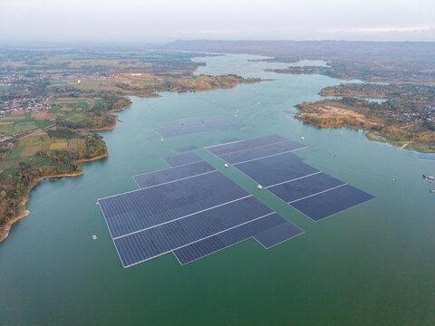 Floating solar panels span wide, calm lake waters. Grids stretch across greenish blue surface at Waduk Karangkates