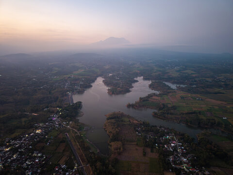 Distant hills frame a quiet, winding river. Villages nestle beside cultivated fields at Waduk Karangkates