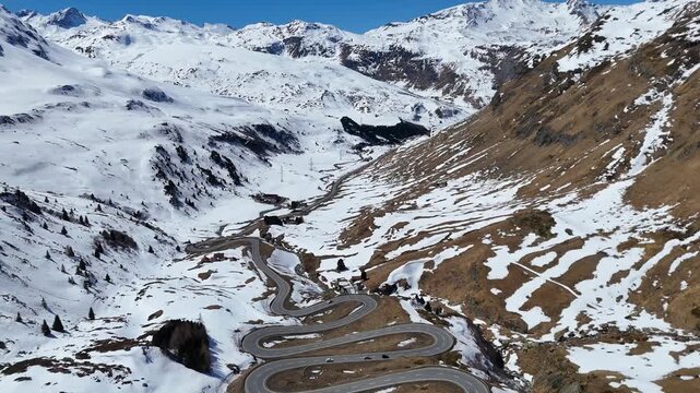 switchback complex unfolds beneath towering snow capped peaks cars wind through hairpin turns julier pass alpine crossing graubunden switzerland small huts drone aerial view high altitude panorama
