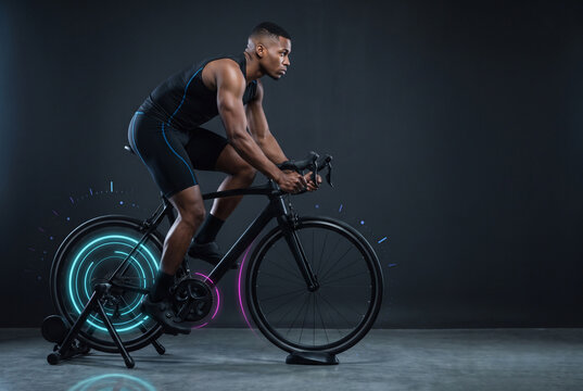 Athlete Riding a Stationary Road Bicycle with Neon Performance Graphics