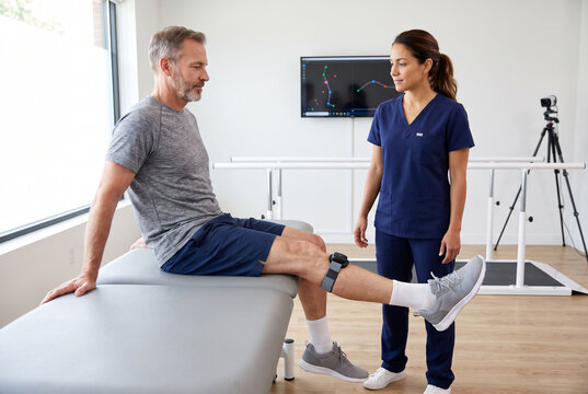 Physical therapist monitoring seated knee extension with motion sensor