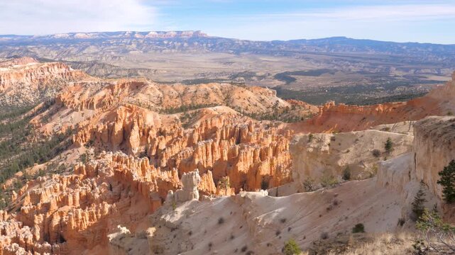 Expansive panoramic view slowly panning across the magnificent bryce canyon amphitheater, revealing its famous orange and red spire-shaped rock formations known as hoodoos on a sunny day