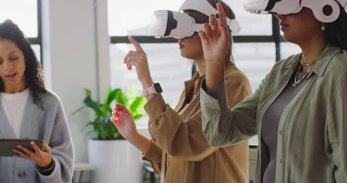 Diverse female team guiding with tablet while two women tapping VR headsets wearing blouses at work