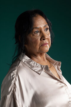 Senior African woman posing in studio wearing cream satin blouse and thin gold necklace