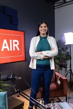 African American woman standing arms crossed smiling at camera in studio with AIR monitor and booms