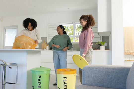 African American family sorting recycling at kitchen island with colorful bins and orange bag
