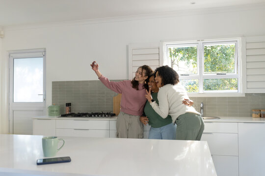 African American family posing for selfie at bright kitchen island with smartphone and green mug
