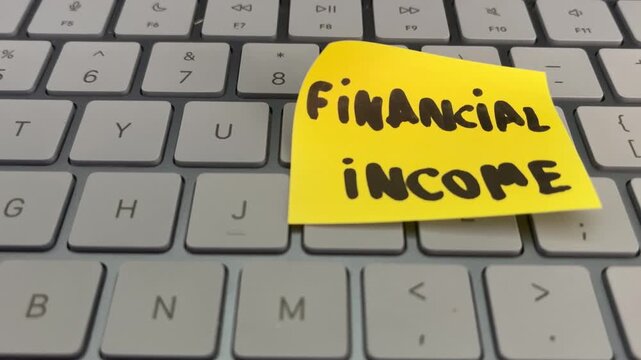 Financial income sticky note on laptop keyboard keys close up