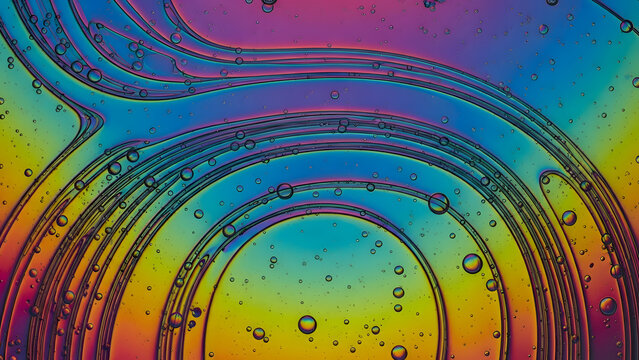 Vibrant rainbow soap film with iridescent colors and reflected light creating a mesmerizing pattern of concentric circles and bubbles