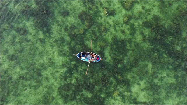 Drone Shot of Small Fishing Boat Rowing in Transparent Emerald Ocean Water